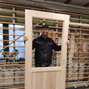 Schreiner-Workshop Pascal Holztür Teilnehmer Pascal hält seine selbst gebaute Holztür mit Glaseinsatz im Schreiner-Workshop.